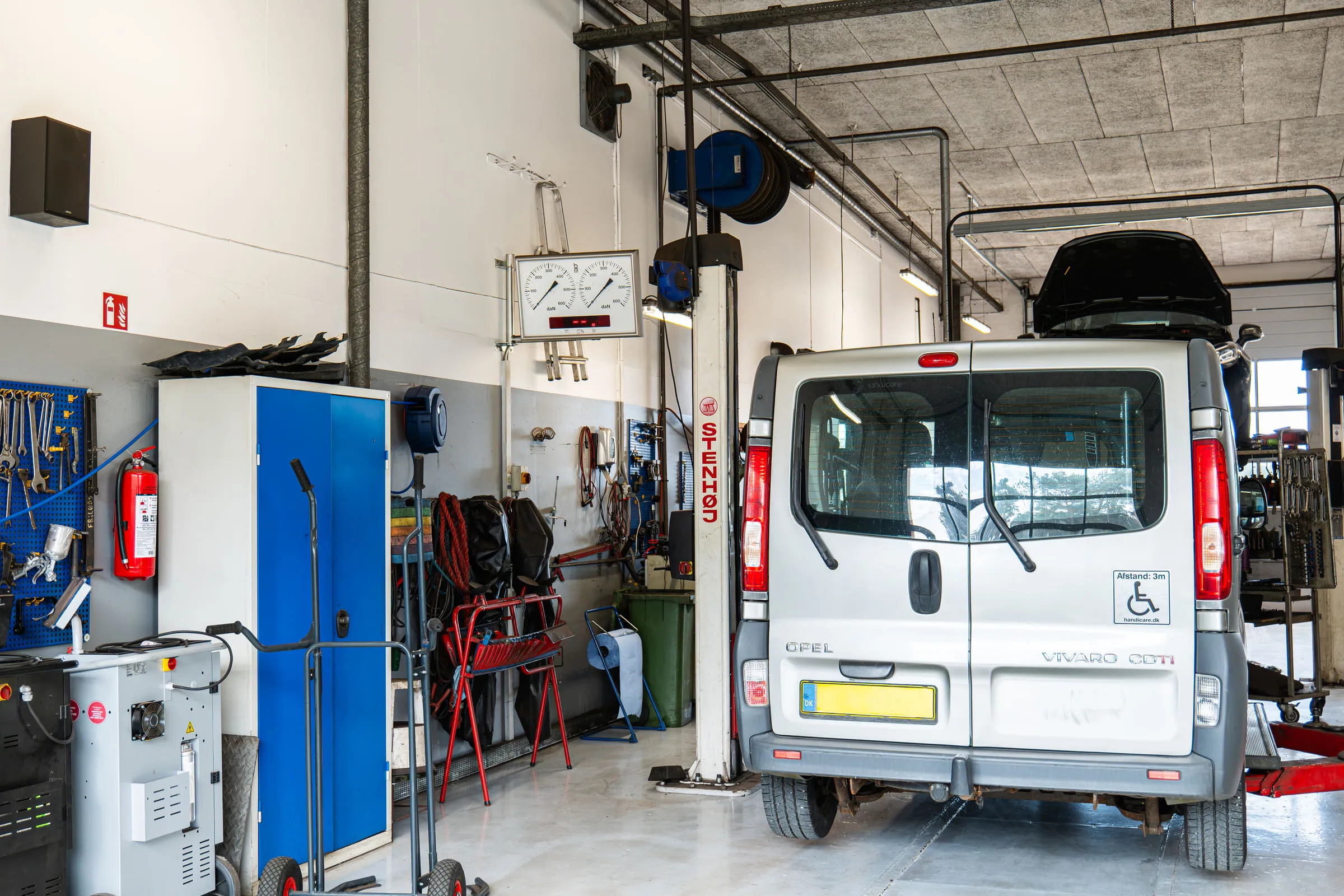 Varebil på lift med motorhjelmen åben under serviceeftersyn